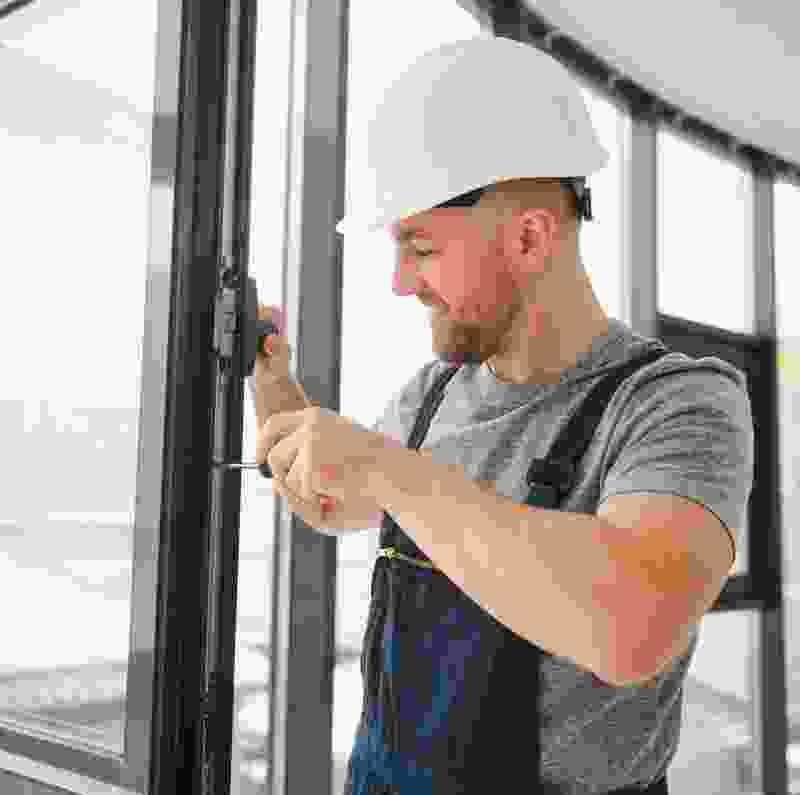 Man in a hard hat installing a window, demonstrating skilled workmanship related to home improvement services.